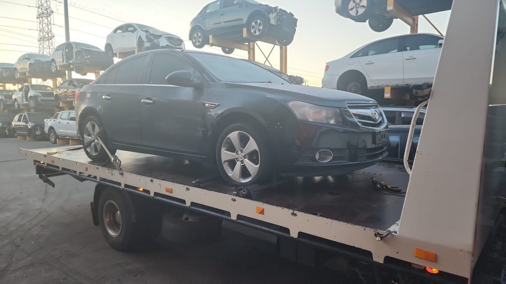 Cash for Scrap Cars Bittern VIC 1 Dark sedan loaded on a white flatbed tow truck in a vehicle yard