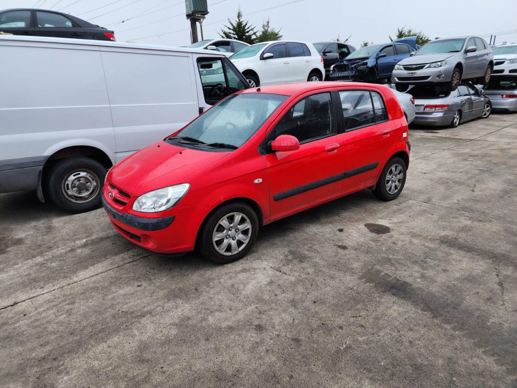 Cash for Scrap Cars Mooroolbark VIC 1 Red hatchback parked beside a white van in a vehicle recycling yard