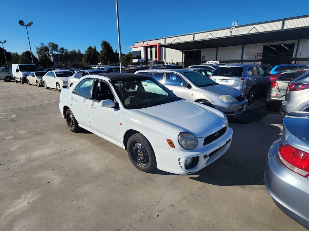 Cash for Scrap Cars Gowanbrae VIC 1 White sedan parked among vehicles in an automotive yard