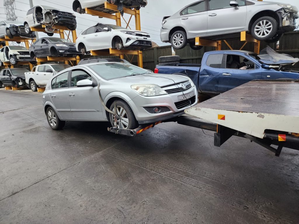 Cash for Scrap Cars Flemington VIC 1 Silver station wagon being winched onto a flatbed in a recycling yard