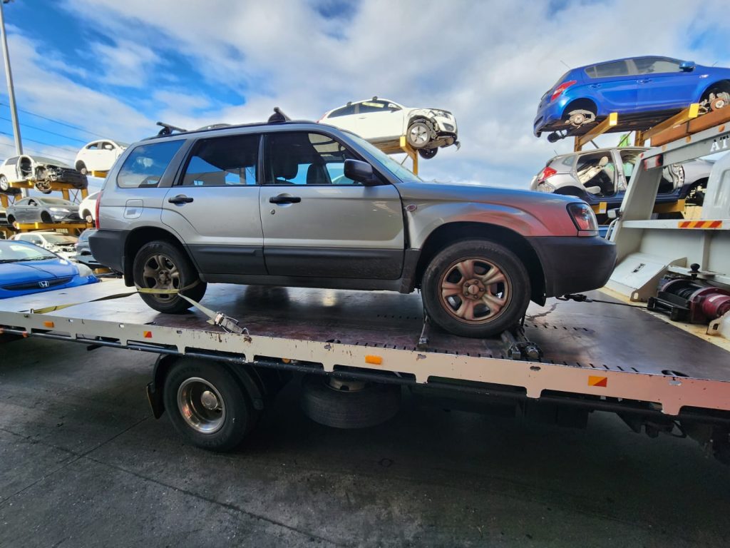 Cash for Scrap Cars Glen Iris VIC 1 Silver SUV on a flatbed with vehicle storage racks behind it